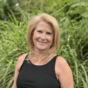 Woman with black tank top in front of bush