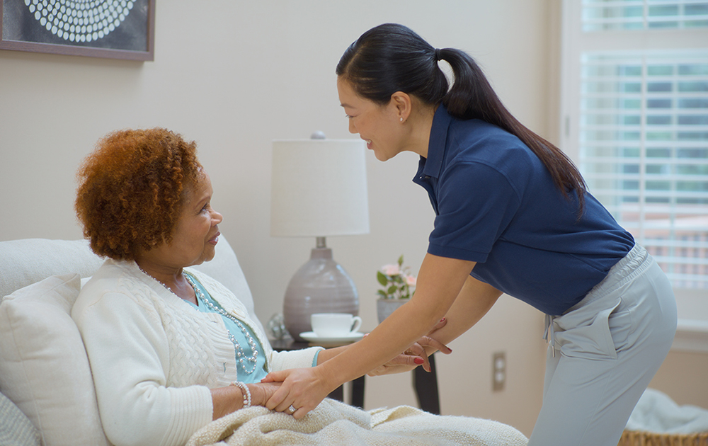 caregiving helping senior woman in bed