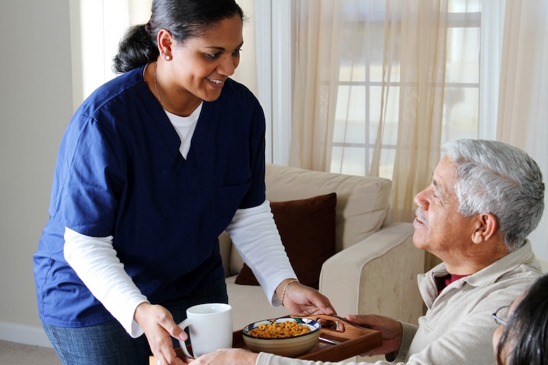 nurse serving meal to a senior man