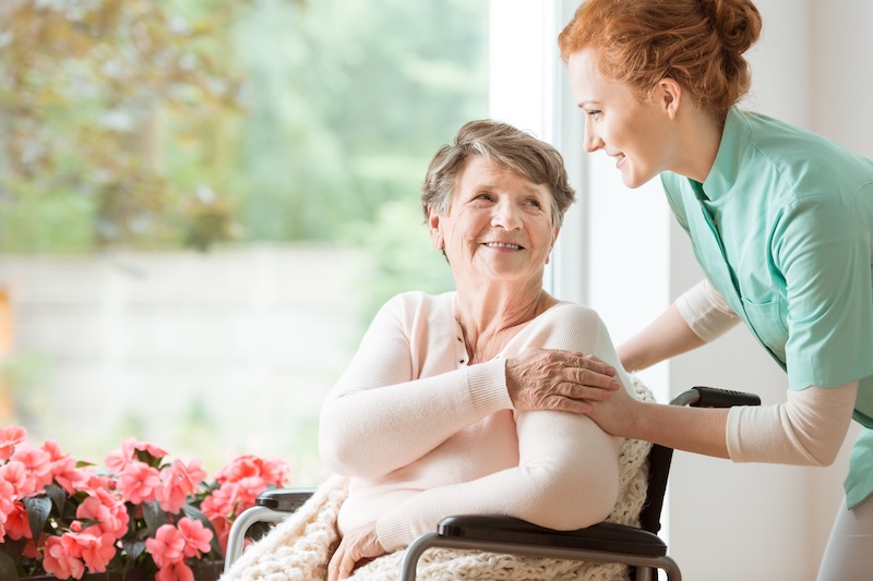 nurse helping an elderly woman in a wheelchair