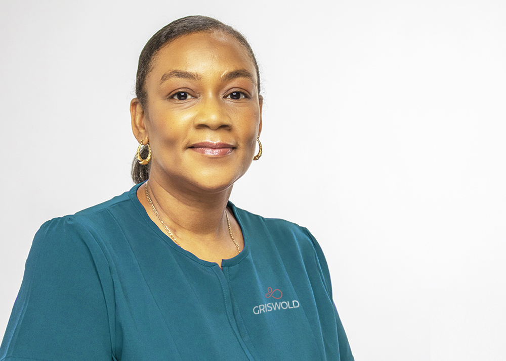 A Caregiver smiling at the camera wearing a peacock Griswold shirt.