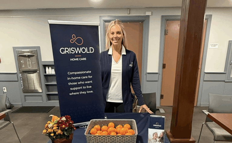 Our Director, Kelly Howard, pictured at a Griswold table while at an event. There is a Griswold banner and a basket of oranges on the table.