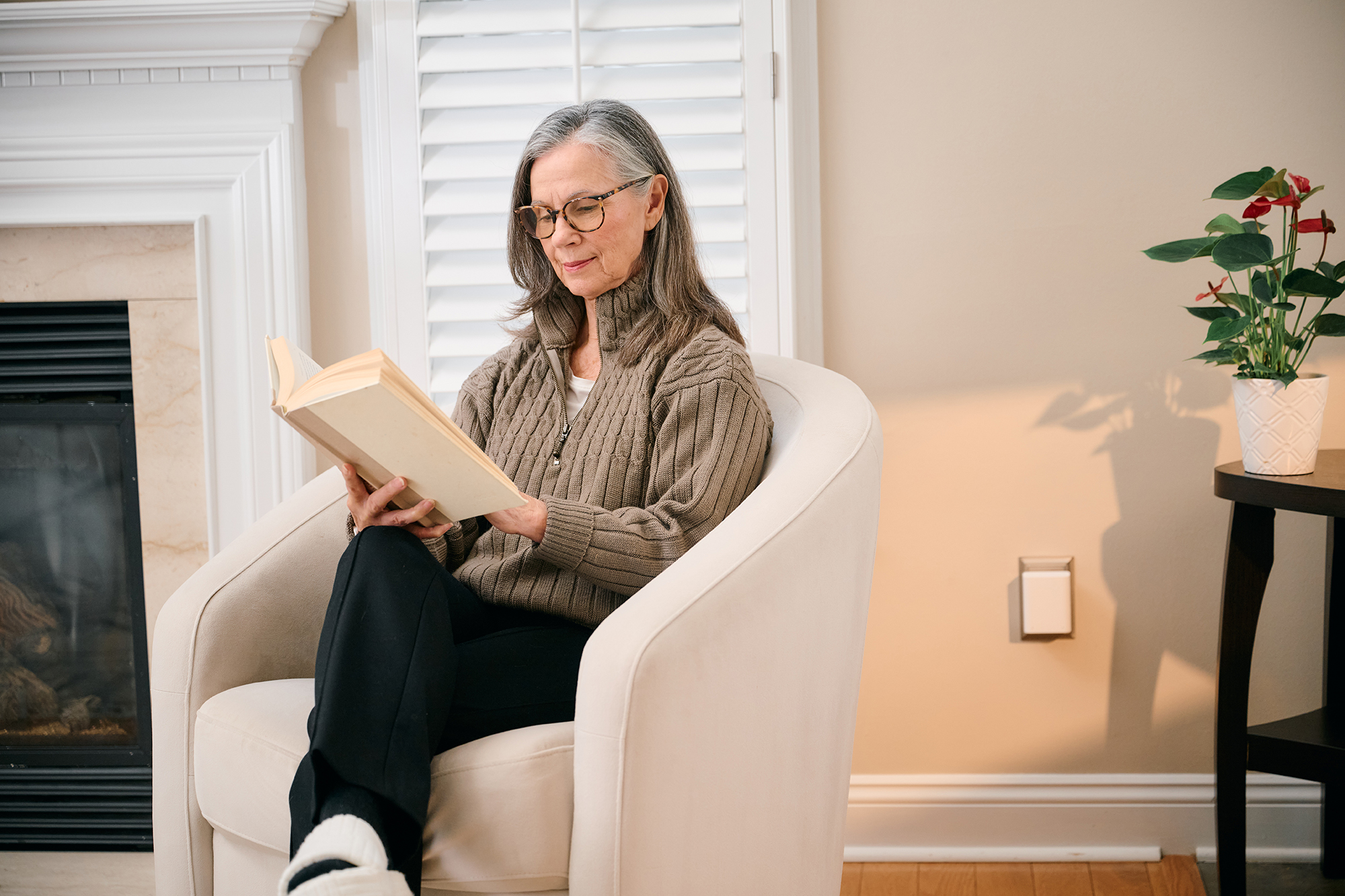 A woman reading with a Sensi pod plugged into the wall behind her.