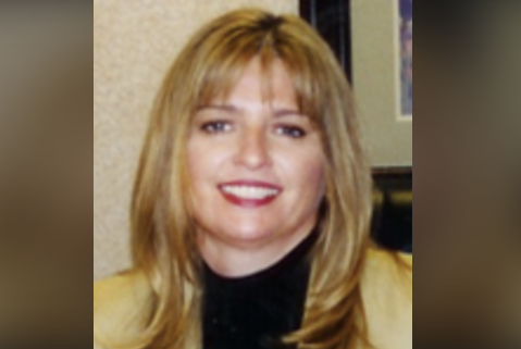 A woman with long blonde hair and a black top, representing a leading home health care service, smiles at the camera.